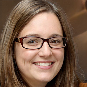 Sophia Clark, woman with glasses and brown shirt, smiling for camera