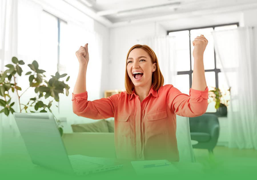 female loan broker with hands in the air, smiling happily, looking at the quality of leads she is receiving on her laptop.