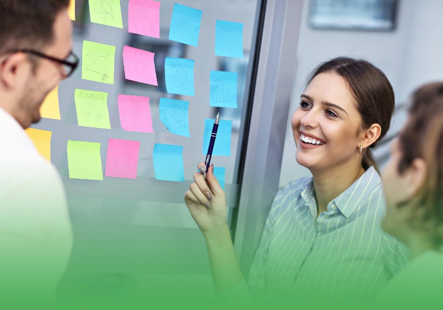 two male brokers and a female putting sticky notes on the office glass door, writing a benefit on each sticky note