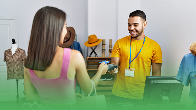 Male employee and female customer stand at cash register engaged in payment transaction at retail business.