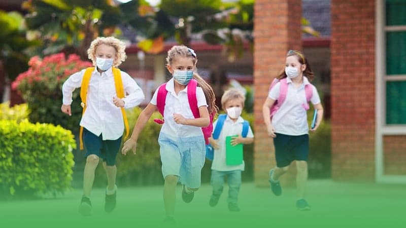 Children at daycare wearing face masks joyfully running school yard under supervision daycare business owner.