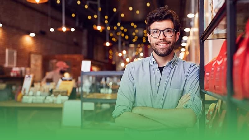 Franchise business owner stands in front of shelf.