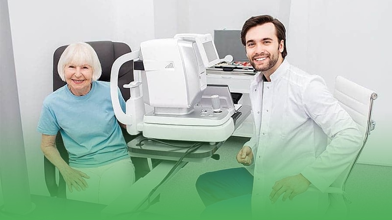 Doctor of optometry and elderly patient sit in front of computer during eye exam.