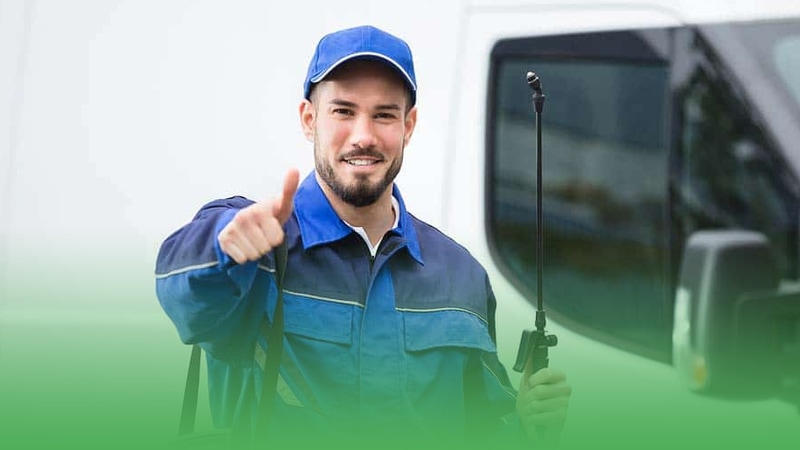 Pest control business owner in blue uniform holds tool.