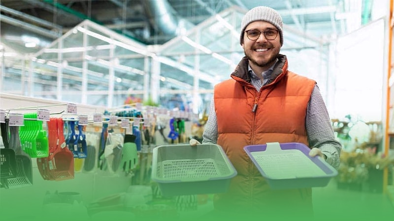 Pet store business owner holding tray of plastic containers in warehouse.