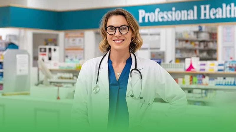 Pharmacy business owner woman in lab coat stands before pharmacy counter.