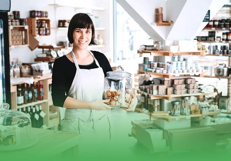 Small business owner holding jar of nuts in store showcasing products in her store