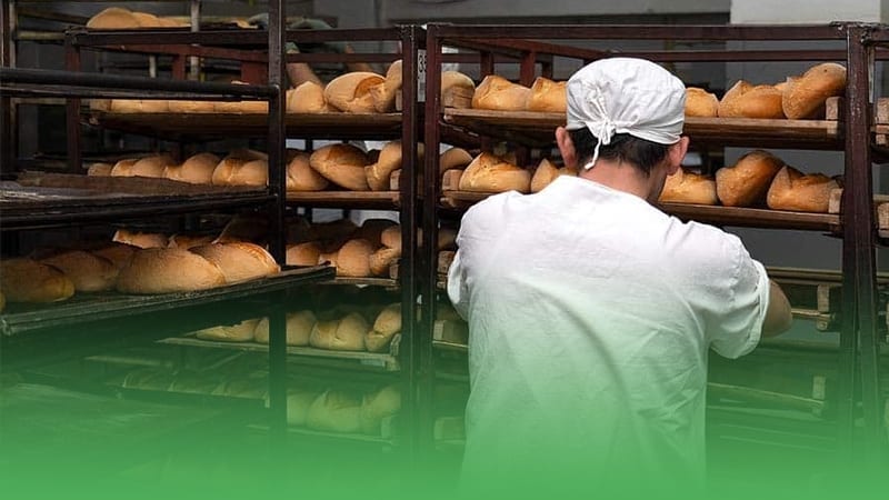 Bakery business owner in white hat hard at work in kitchen preparing delicious treats for customers.