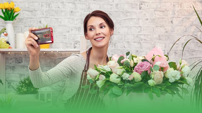 Florist business owner holds flowers and credit card for payment