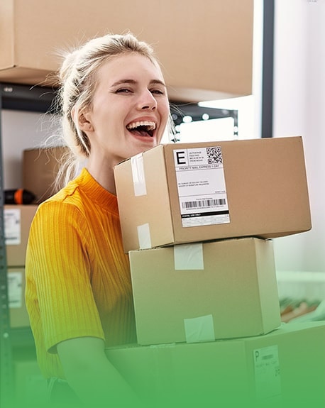 happy female business owner carrying product boxes she is about to ship to customers