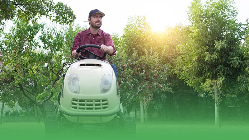 Man on lawn mower in park representing lawn care business.